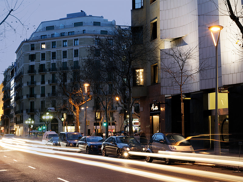 Rua residencial em Barcelona iluminada por postes de via ao entardecer